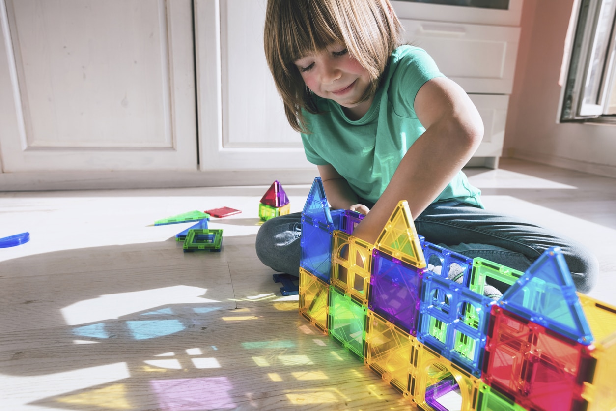 Young girl playing with colorful see through blocks on the ground