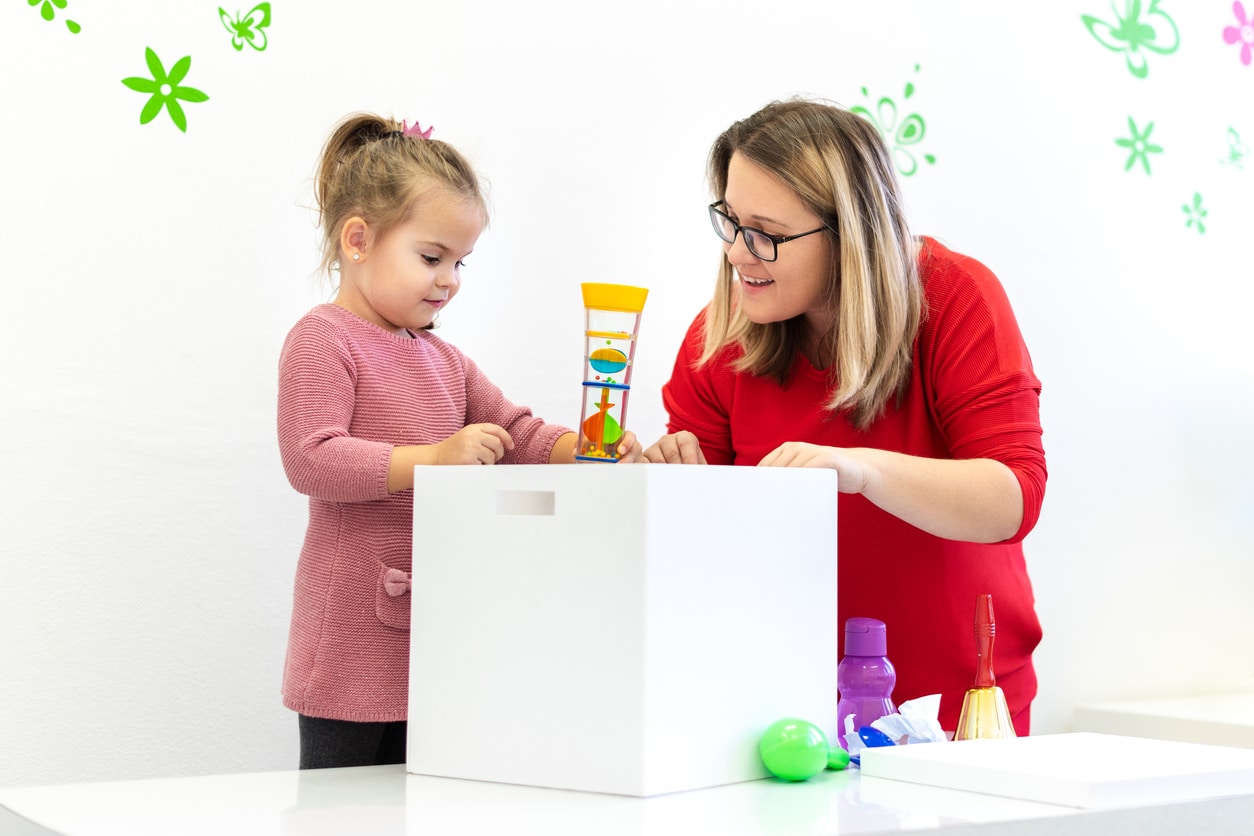 Young girl playing with toys in her room with her occupational therapist