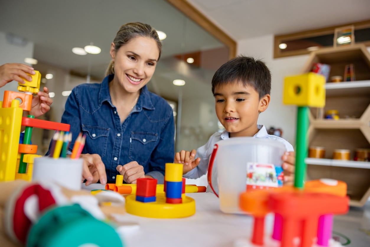 Young boy playing with building blocks on a table with his occupational therapist