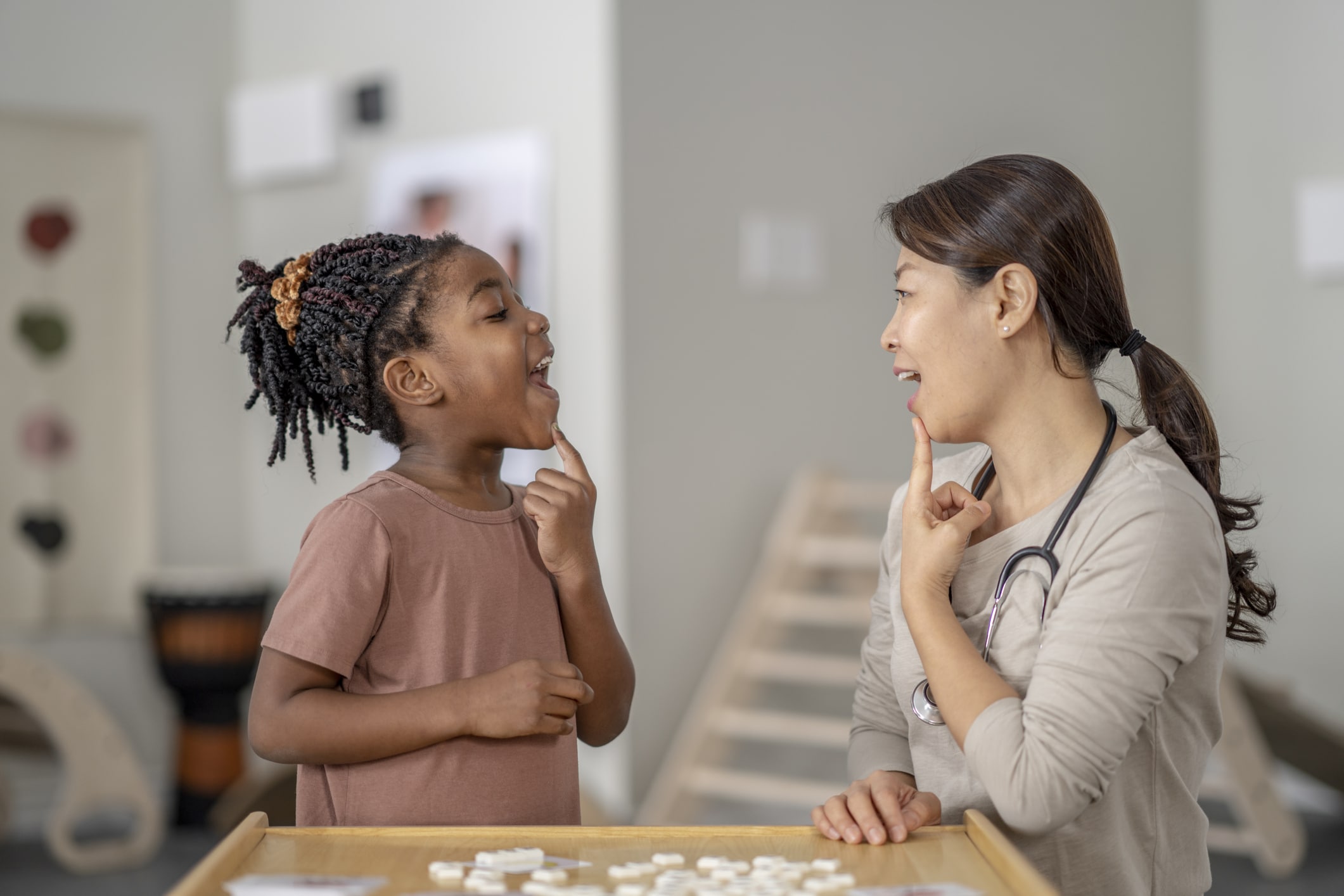 Speech therapist and child at a table practicing letter sounds during pediatric speech delay treatment