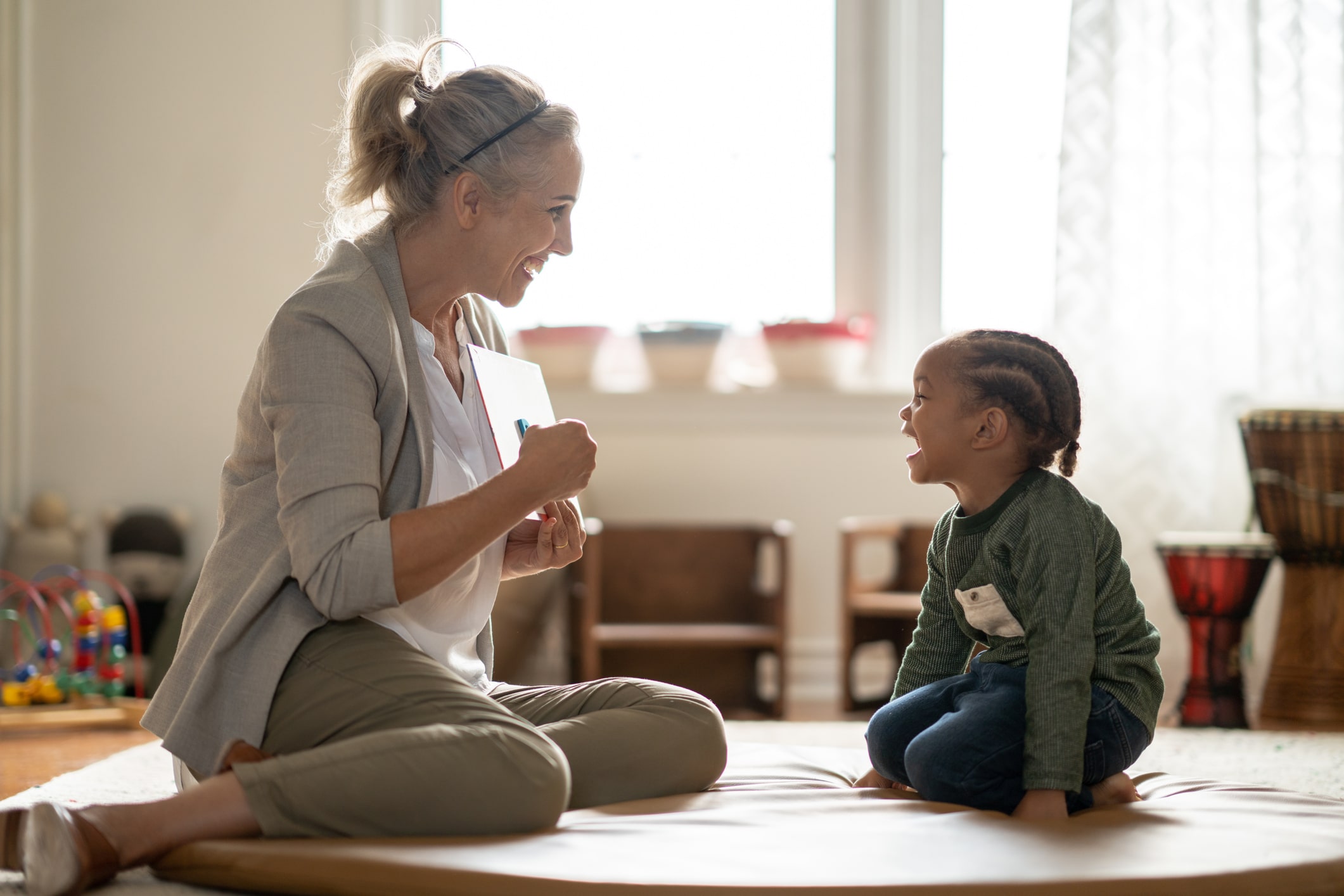 Speech therapist sitting on the floor with young child during an in-home speech therapy session